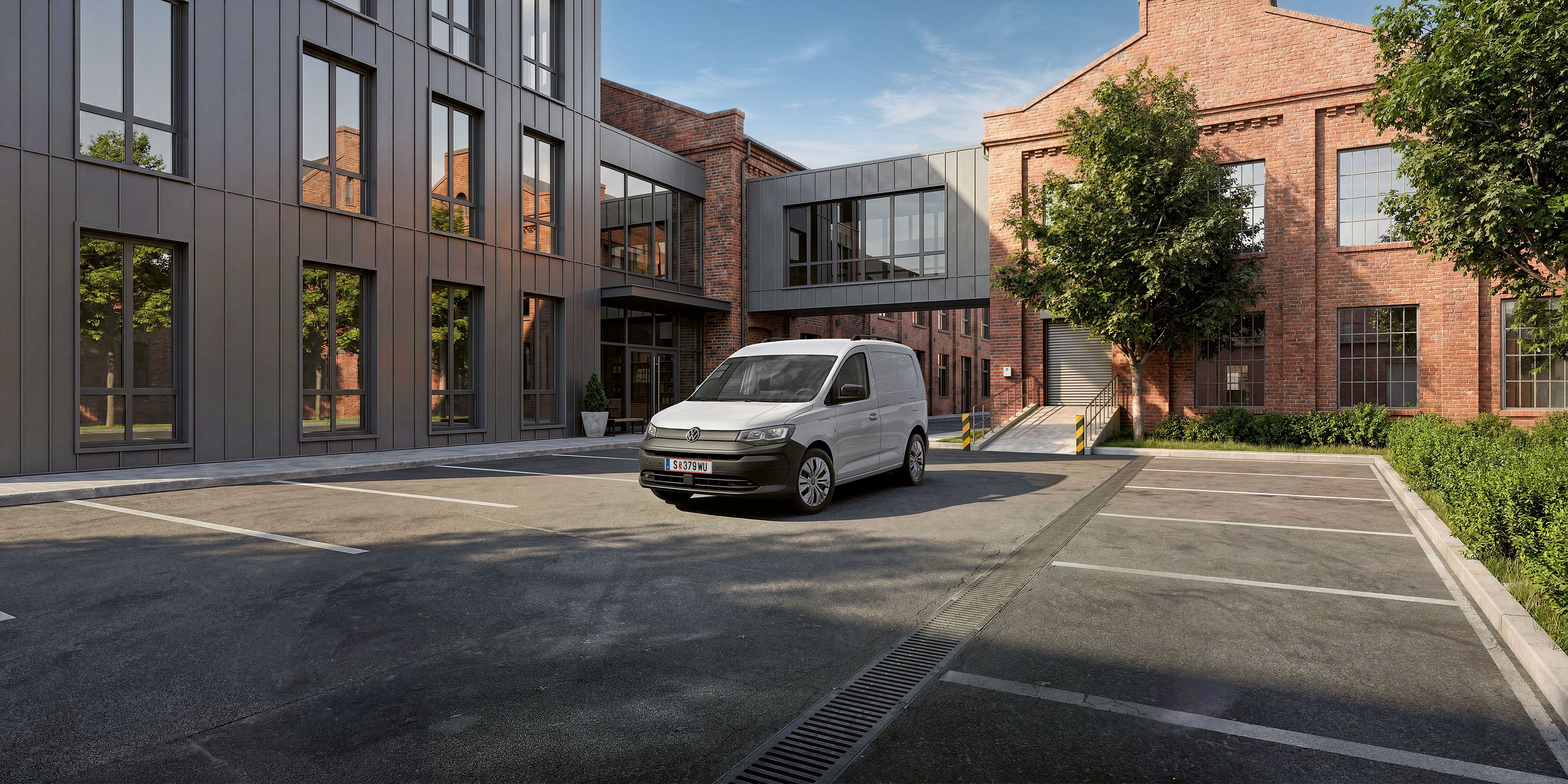 Der neue Caddy Cargo in Weiß steht vor Gebäude.