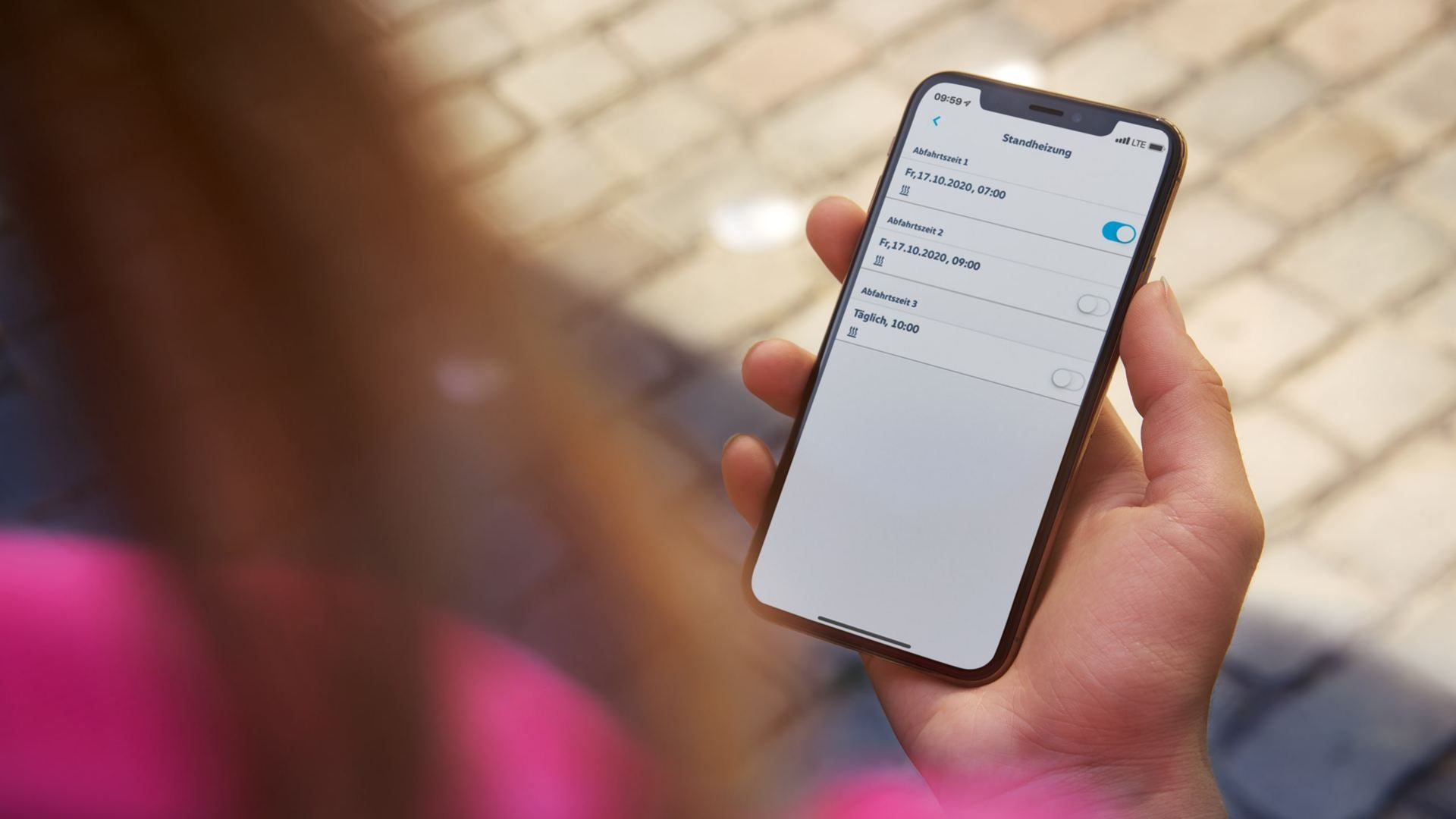Eine Frau aktiviert über ihr Handy die Standheizung ihres Autos